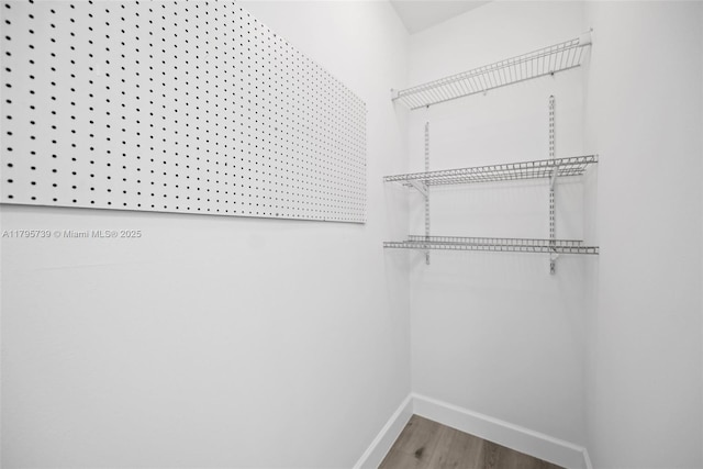 walk in closet with wood finished floors