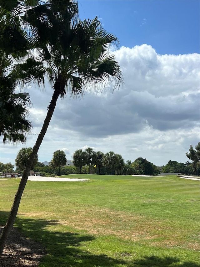 view of home's community with view of golf course and a yard