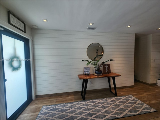 corridor with wooden walls, baseboards, visible vents, and wood finished floors
