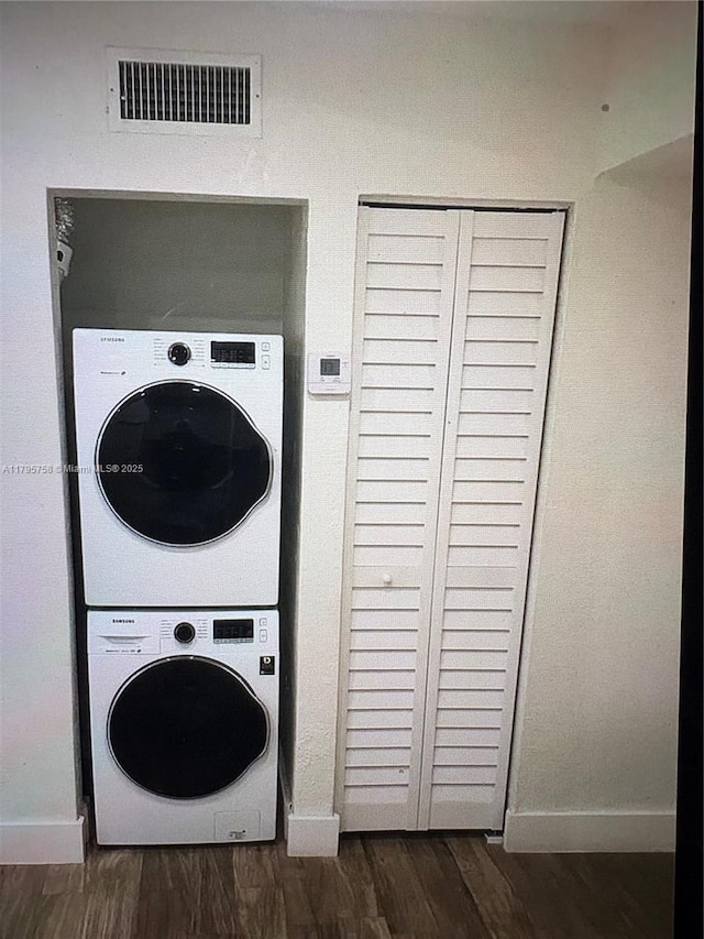 laundry room with laundry area, visible vents, baseboards, stacked washing maching and dryer, and dark wood-type flooring