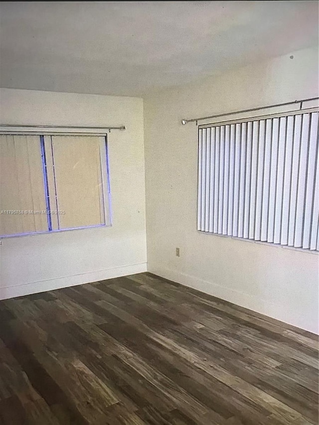 unfurnished room with baseboards and dark wood finished floors