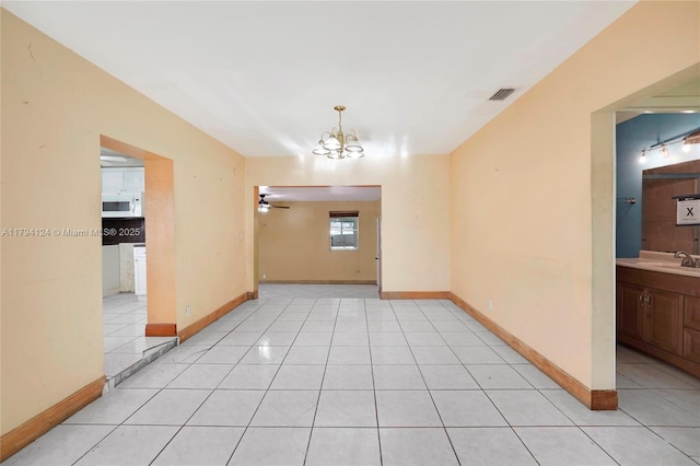 4241 W 1st Ave, Hialeah, FL 33012 - empty room with visible vents, a sink, ceiling fan with notable chandelier, and light tile patterned flooring