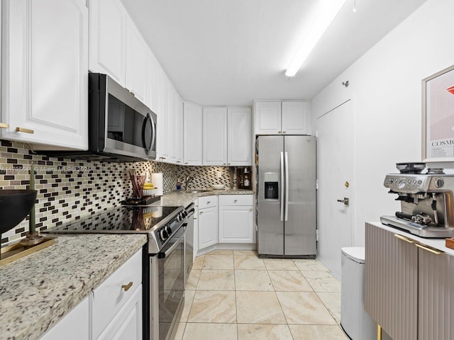 6039 Collins Ave Unit 1015, Miami Beach, FL 33140 - kitchen with white cabinets, stainless steel appliances, light stone counters, and decorative backsplash