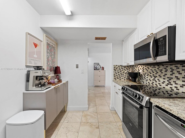 6039 Collins Ave Unit 1015, Miami Beach, FL 33140 - kitchen featuring white cabinets, appliances with stainless steel finishes, marble finish floor, baseboards, and backsplash