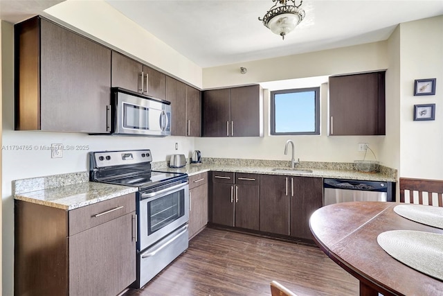 3300 NE 191st St Unit 07, Aventura, FL 33180 - kitchen with appliances with stainless steel finishes, a sink, dark brown cabinets, dark wood-style floors, and light stone counters