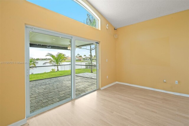 18506 NW 24th Pl, Pembroke Pines, FL 33029 - unfurnished room featuring a water view, light wood finished floors, baseboards, a textured ceiling, and lofted ceiling