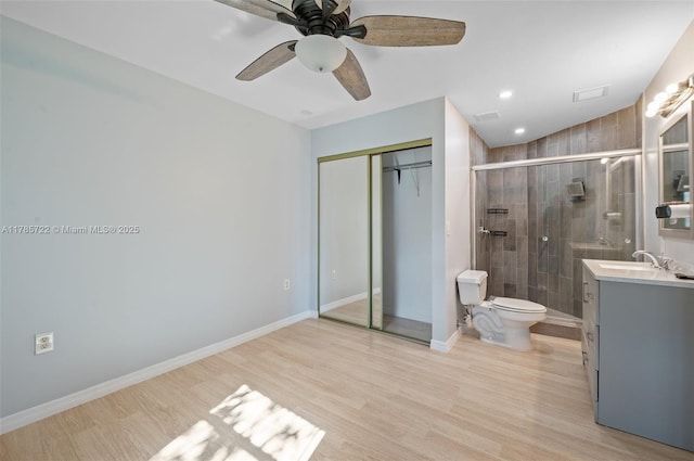 full bath featuring vanity, wood finished floors, toilet, a shower stall, and a ceiling fan
