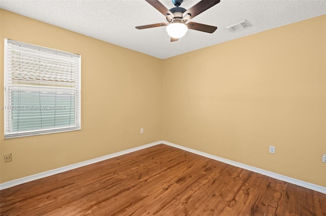 unfurnished room featuring visible vents, wood finished floors, baseboards, ceiling fan, and a textured ceiling