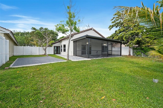 rear view of property featuring stucco siding, a sunroom, a fenced backyard, a lawn, and a patio