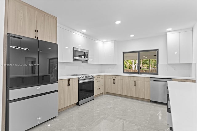 kitchen with marble finish floor, light brown cabinetry, light countertops, a sink, and stainless steel appliances