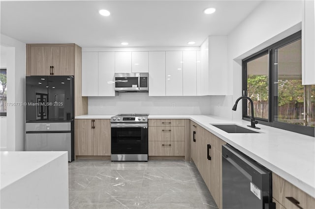 kitchen with modern cabinets, recessed lighting, light countertops, a sink, and stainless steel appliances