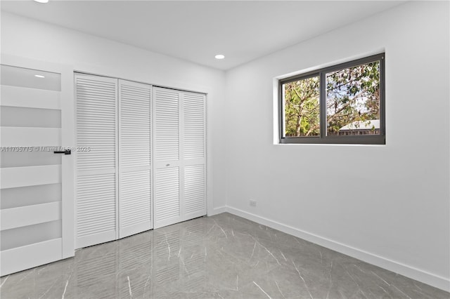 unfurnished bedroom featuring recessed lighting, baseboards, marble finish floor, and a closet