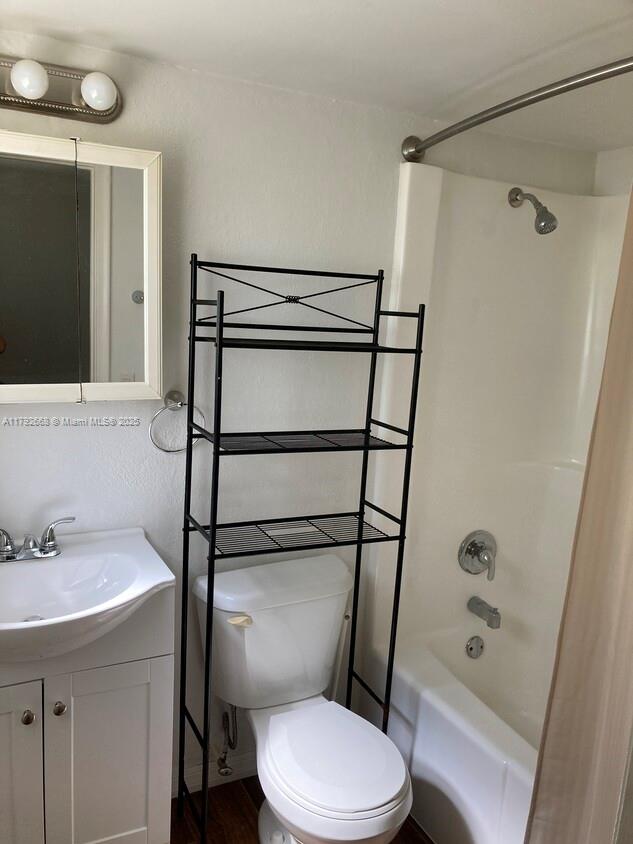 full bath featuring toilet, vanity,  shower combination, and wood finished floors
