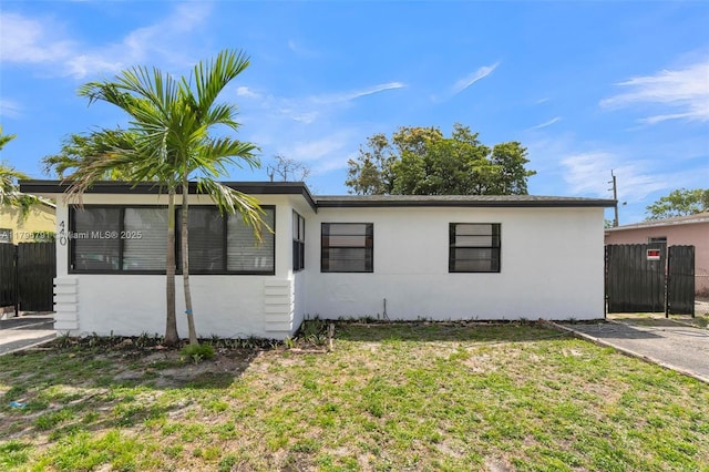 ranch-style home with stucco siding, fence, and a front yard