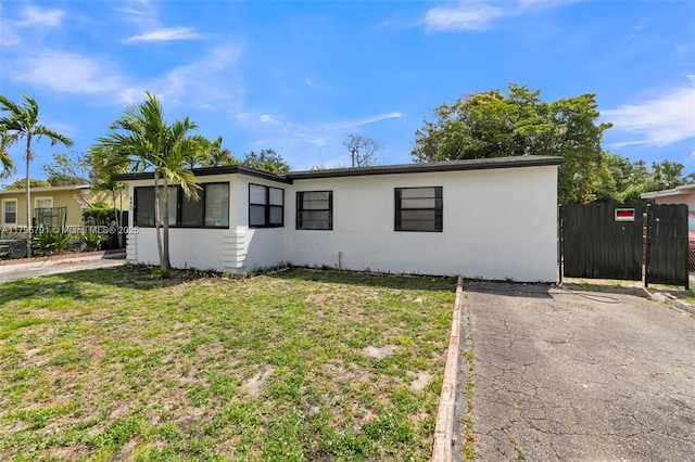 ranch-style home with stucco siding, a front lawn, and fence