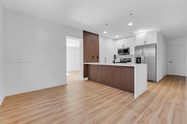 kitchen with light wood-type flooring, recessed lighting, white cabinetry, light countertops, and appliances with stainless steel finishes