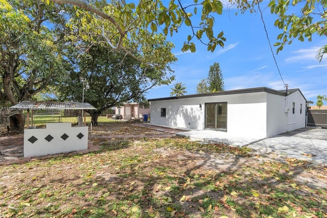 rear view of house with fence and stucco siding