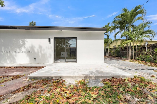 back of house with fence, a patio, and stucco siding