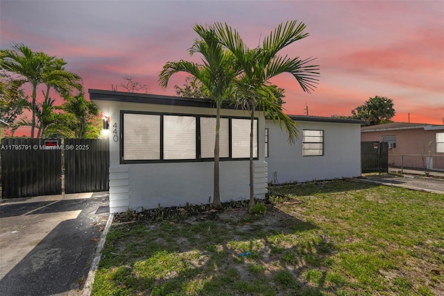 view of front of house featuring a lawn, fence, and stucco siding