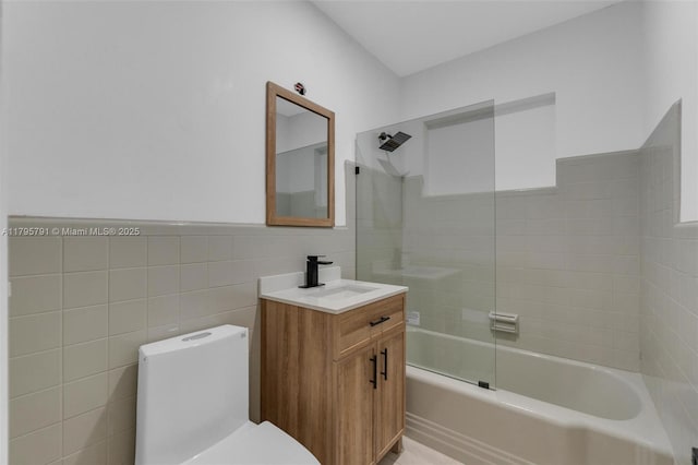 full bath featuring vanity, toilet, a wainscoted wall, tile walls, and tub / shower combination