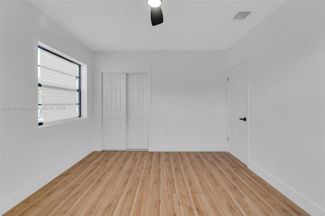 unfurnished bedroom featuring visible vents, baseboards, a closet, and hardwood / wood-style floors