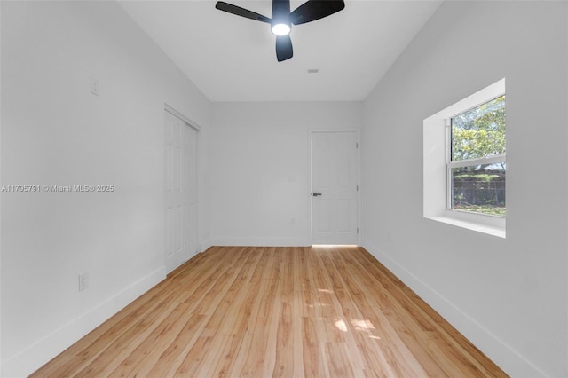 empty room with wood-type flooring, a ceiling fan, and baseboards