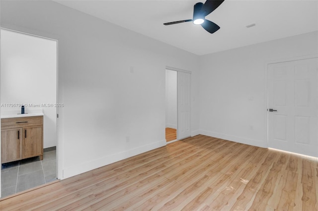empty room with baseboards, light wood finished floors, and ceiling fan