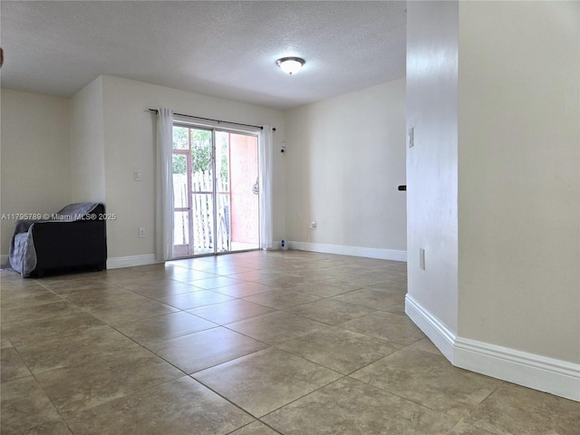 spare room with baseboards and a textured ceiling