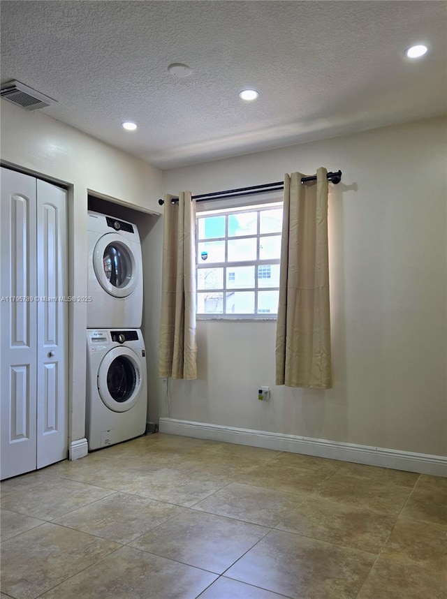 clothes washing area featuring baseboards, stacked washer and clothes dryer, recessed lighting, and a textured ceiling