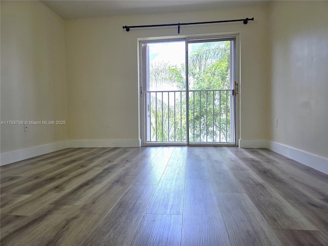 unfurnished room featuring baseboards and wood finished floors