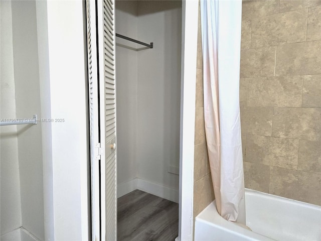 bathroom featuring baseboards, shower / bath combo, and wood finished floors