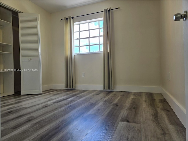 unfurnished bedroom featuring baseboards, wood finished floors, and a closet