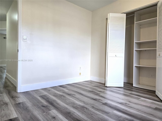 unfurnished bedroom with baseboards, a closet, and wood finished floors