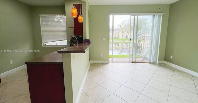 kitchen with baseboards, a peninsula, light tile patterned flooring, and dark countertops