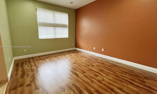 unfurnished room featuring baseboards and wood finished floors