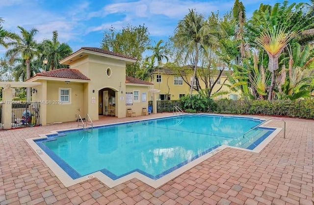 community pool with a patio and fence