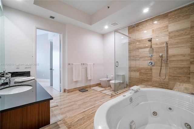 bathroom with a jetted tub, double vanity, a tile shower, a sink, and recessed lighting