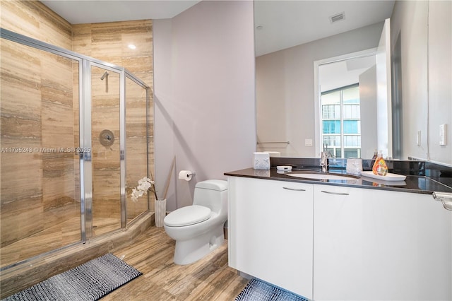 full bath with visible vents, a stall shower, wood finished floors, vanity, and toilet
