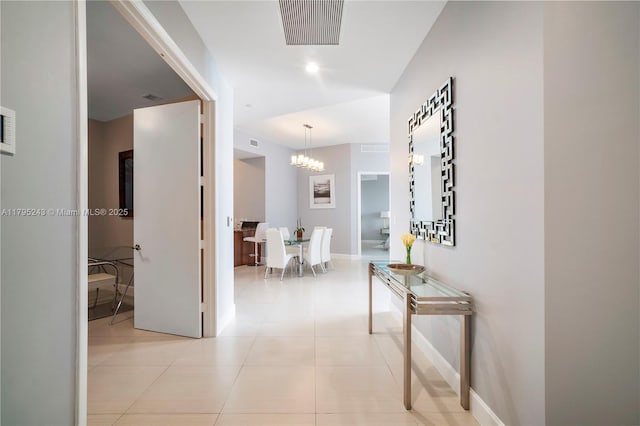 corridor featuring baseboards, a notable chandelier, visible vents, and light tile patterned floors