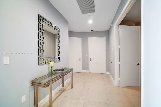 hallway with visible vents, baseboards, and light tile patterned floors