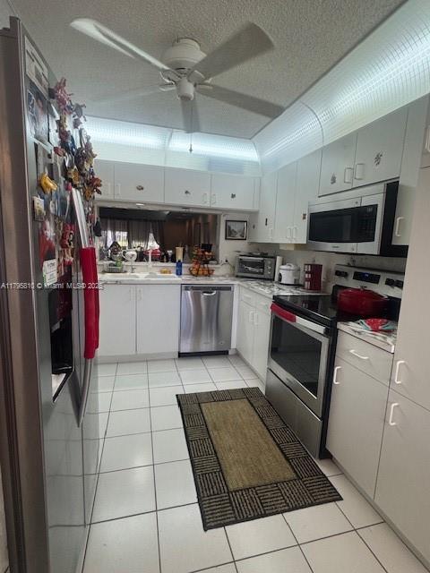 kitchen with light tile patterned flooring, light countertops, appliances with stainless steel finishes, and a ceiling fan