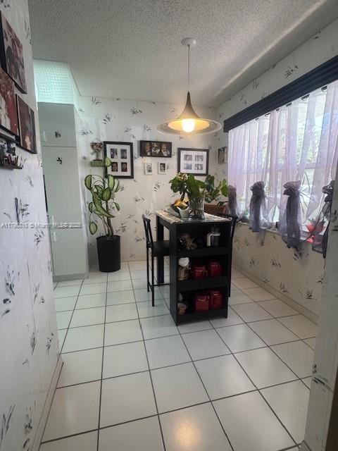 dining space featuring wallpapered walls and a textured ceiling