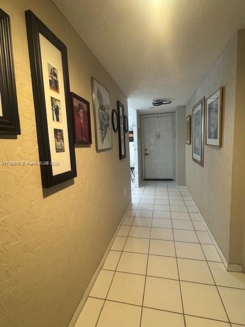 hall featuring baseboards and light tile patterned floors