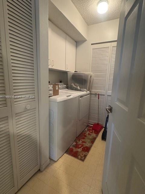 clothes washing area featuring cabinet space, light floors, washer and dryer, and a textured ceiling