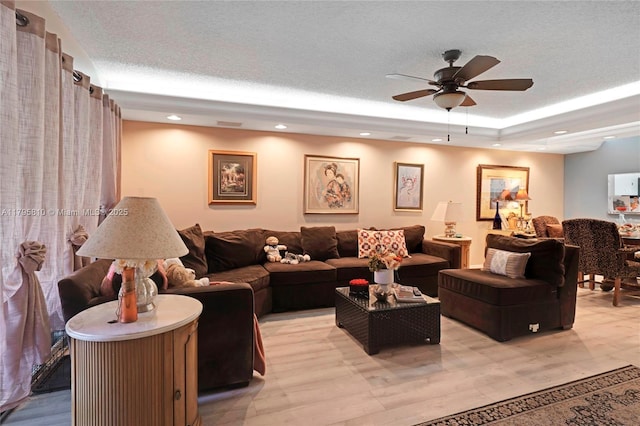 living room with ceiling fan, a raised ceiling, and recessed lighting