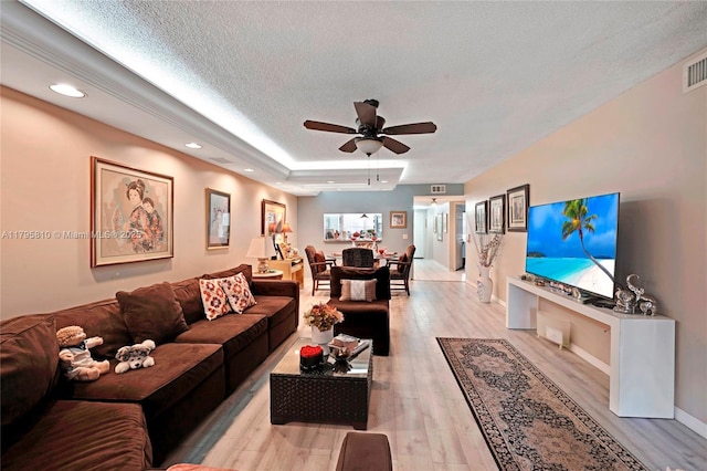 living room featuring ceiling fan, light wood-style floors, a textured ceiling, recessed lighting, and baseboards