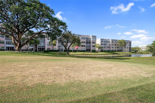 surrounding community with a water view and a lawn