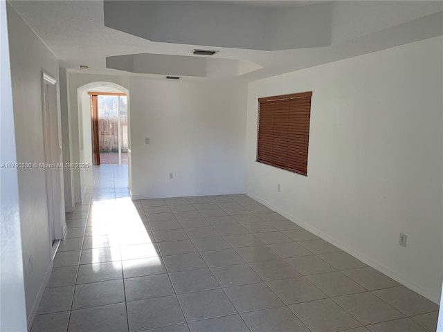 unfurnished room with arched walkways, visible vents, and light tile patterned floors
