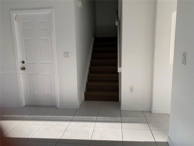 stairway with baseboards and tile patterned flooring