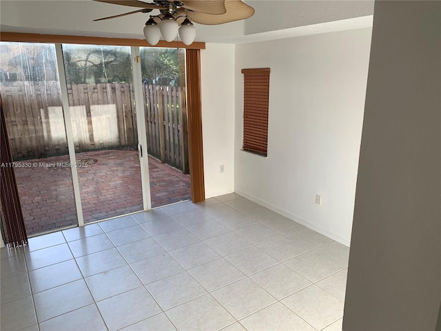 tiled empty room featuring a ceiling fan and baseboards